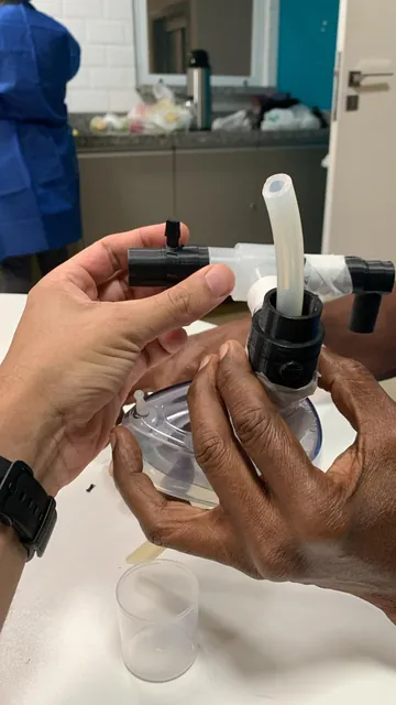 Mãos manuseando uma versão impressa em preto do dispositivo acoplada à máscara
