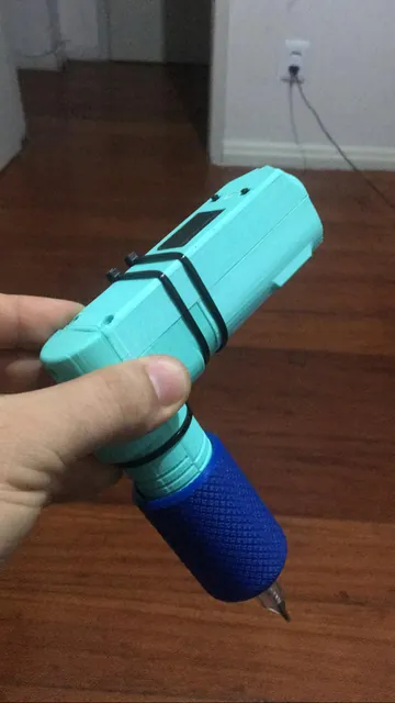 Protótipo de máquina de tatuagem verde-água visto de outro ângulo, segurado na mão