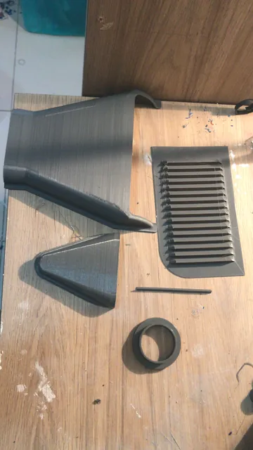 Peças cinzas impressas em miniatura, curvas, com uma grade com aletas e um anel