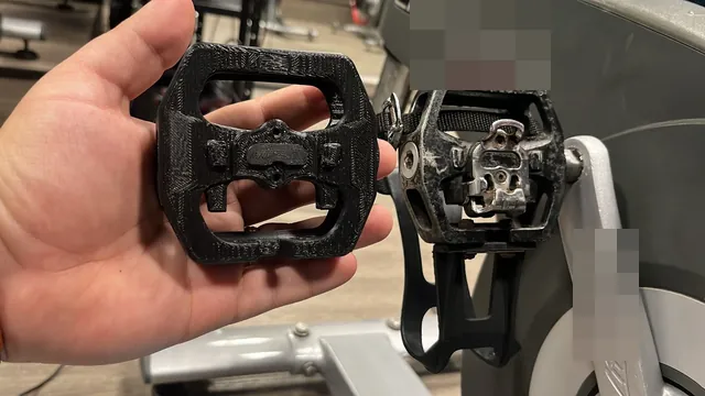 Pedal novo, em polímero preto, ao lado do pedal original, em uma bicicleta